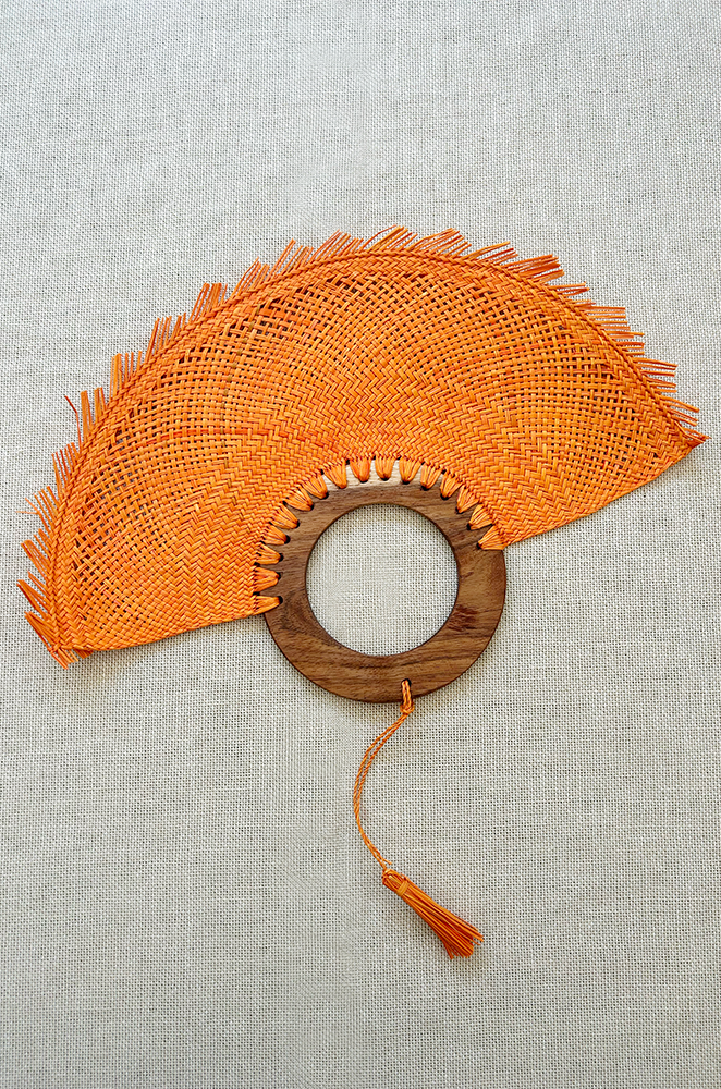 An orange circular palm hand fan with wooden handle