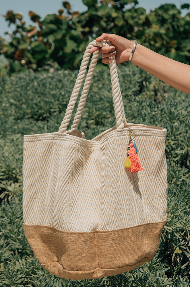 oversized beach tote made of white cotton canvas with a burlap bottom held by a hand