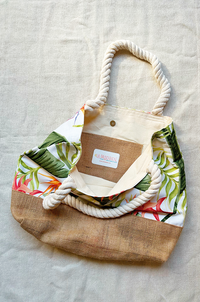 Burlap and cotton tote bag with rope handles on a light fabric background.