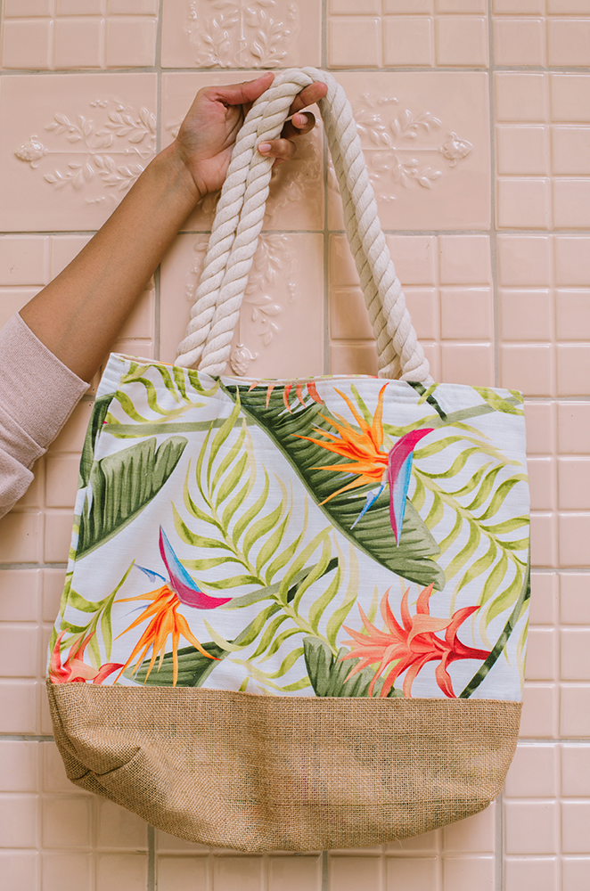 jute beach bag with a tropical print on a pink wall background