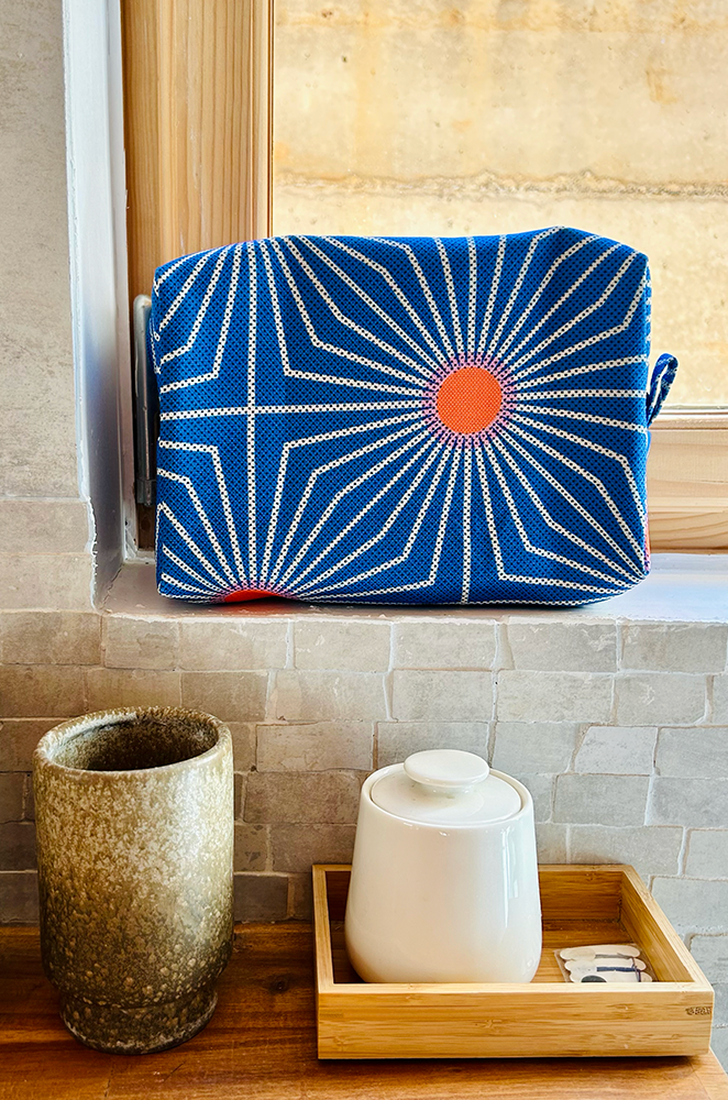 a blue large toiletry bag in a zen bathroom.